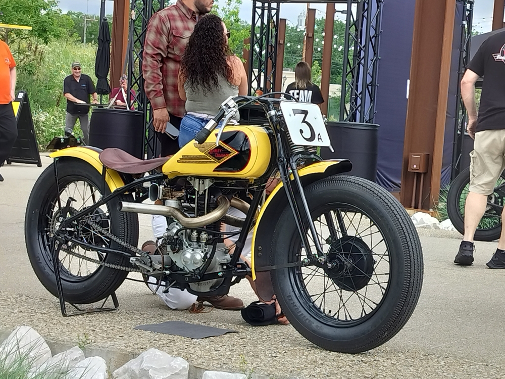 Pre-war Harley-Davidson single cylinder race bike. Yellow tank, brown seat, black frame. Dual exhaust on a singe valve head.