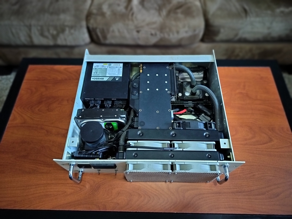 Top view of internal components. Dual 240mm aluminum radiators, watercooled Titan Xp and Ryzen 9 5950X, two mechanical storage drives, Corsair 850W power supply, and Gigabyte ITX motherboard with Corsair RAM.