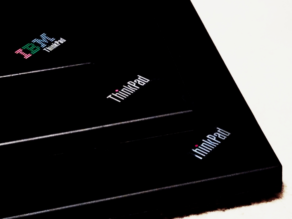 Edited abstract photo of three IBM/Lenovo ThinkPads stacked in a stair step configuration with the main logo at each corner.