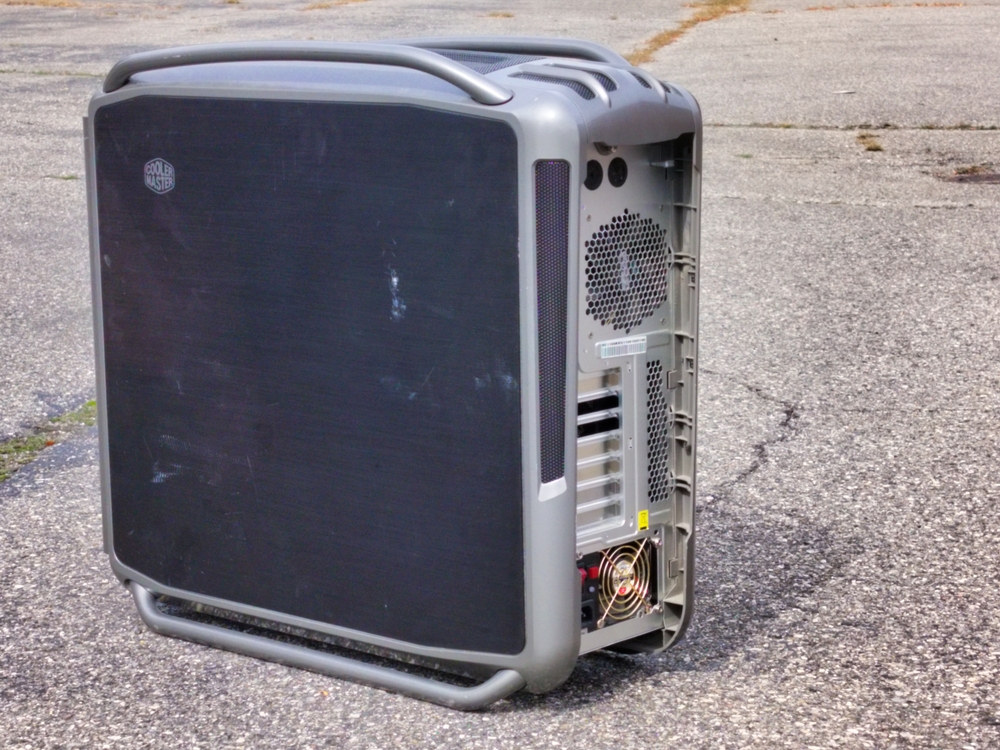 Cosmos S in a parking lot. Rear view showing power supply. The case is covered in dust and grime.